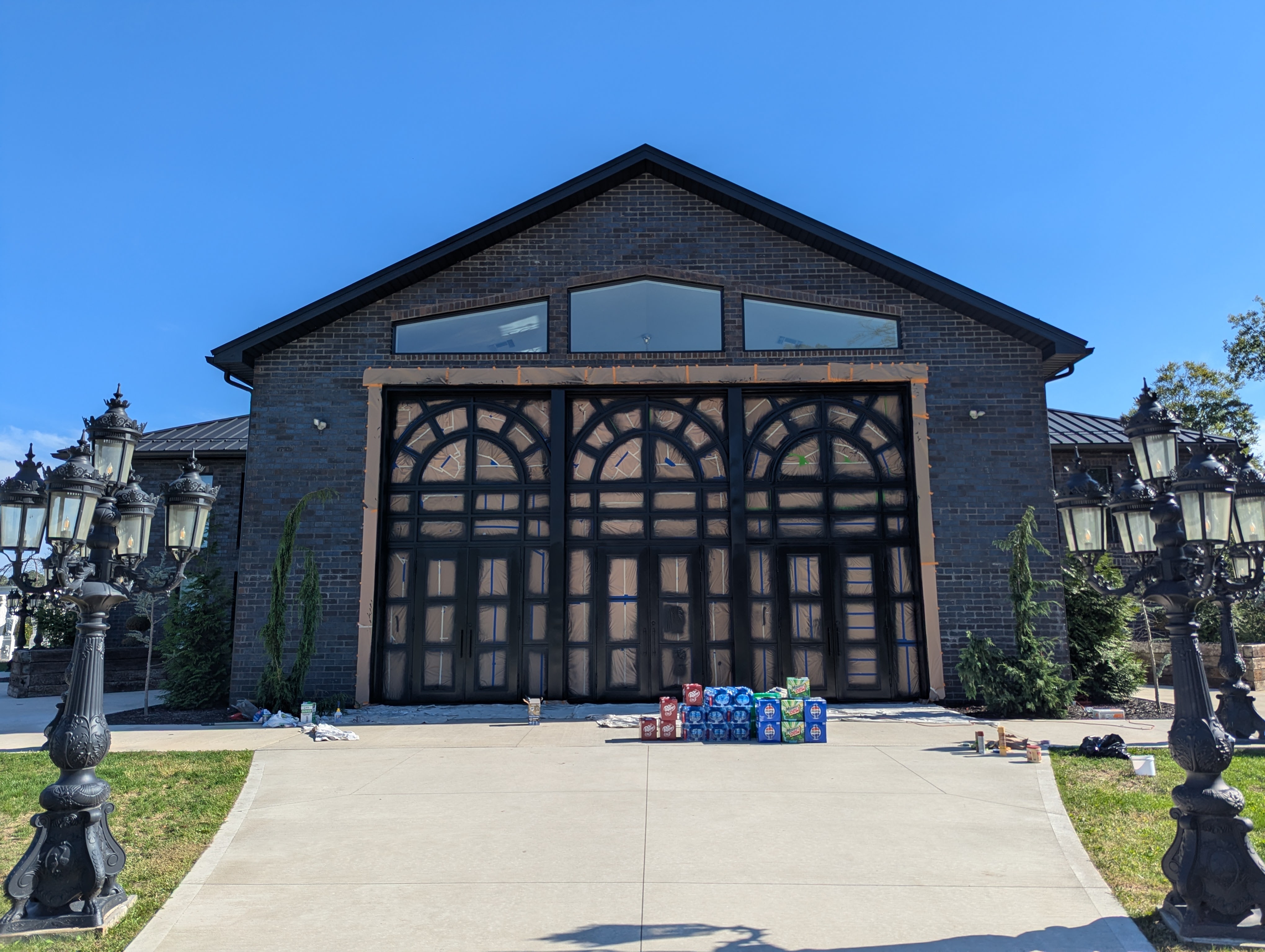 Large brick home with black doors and ornate lampposts.