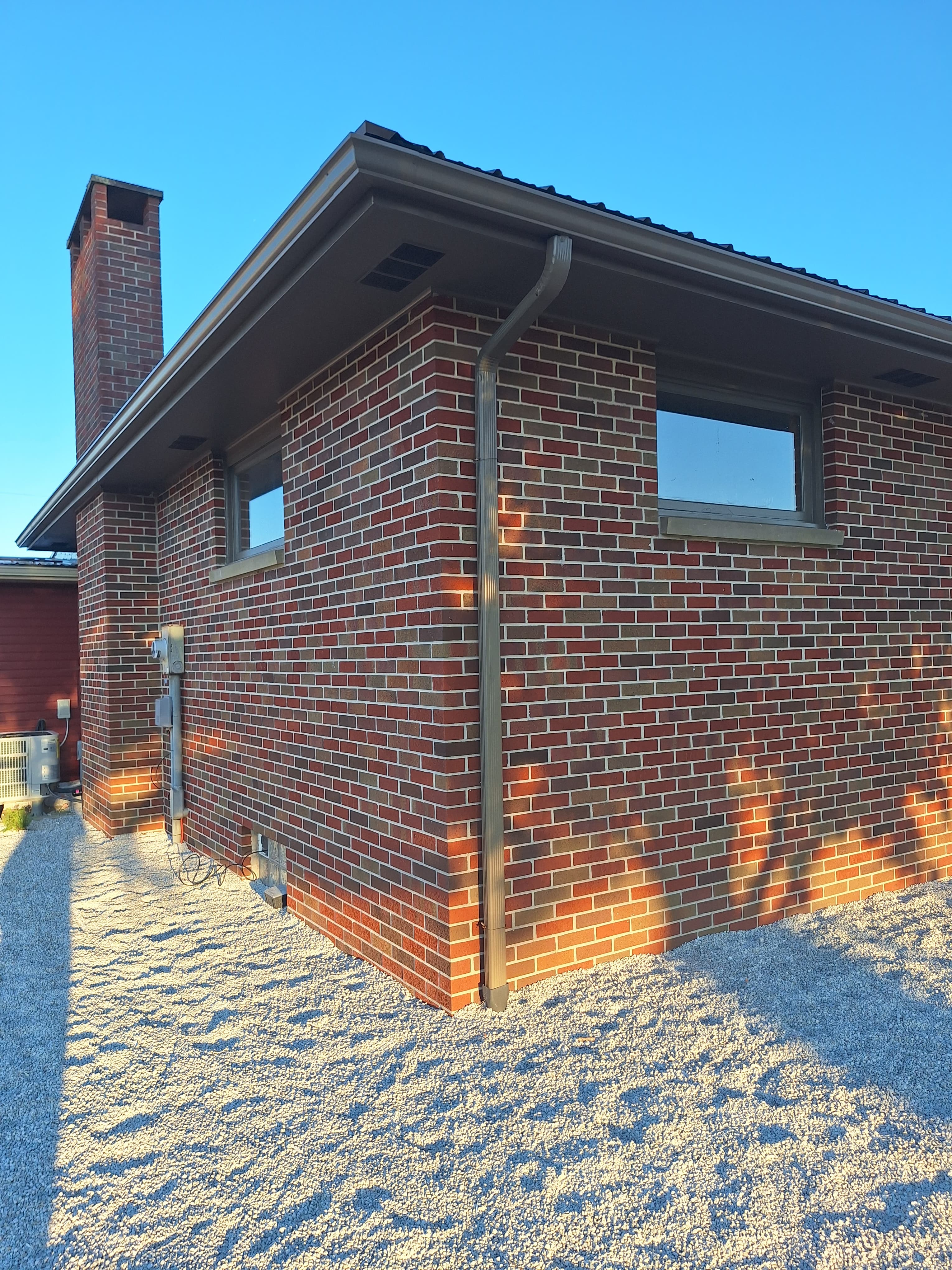 Exterior of a modern brick house with a chimney and gravel landscaping.
