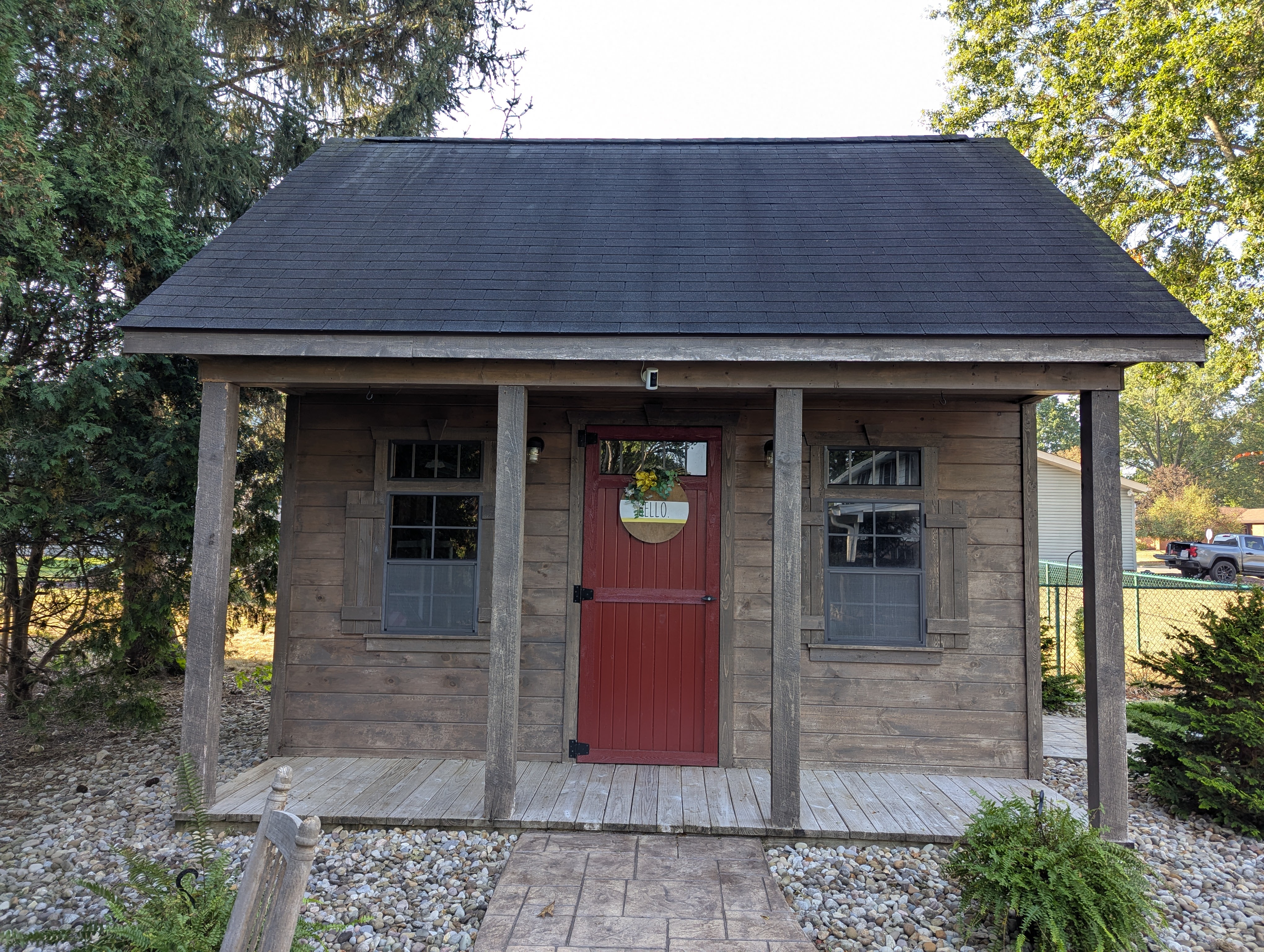 Rustic wooden shed with a red door and small porch.