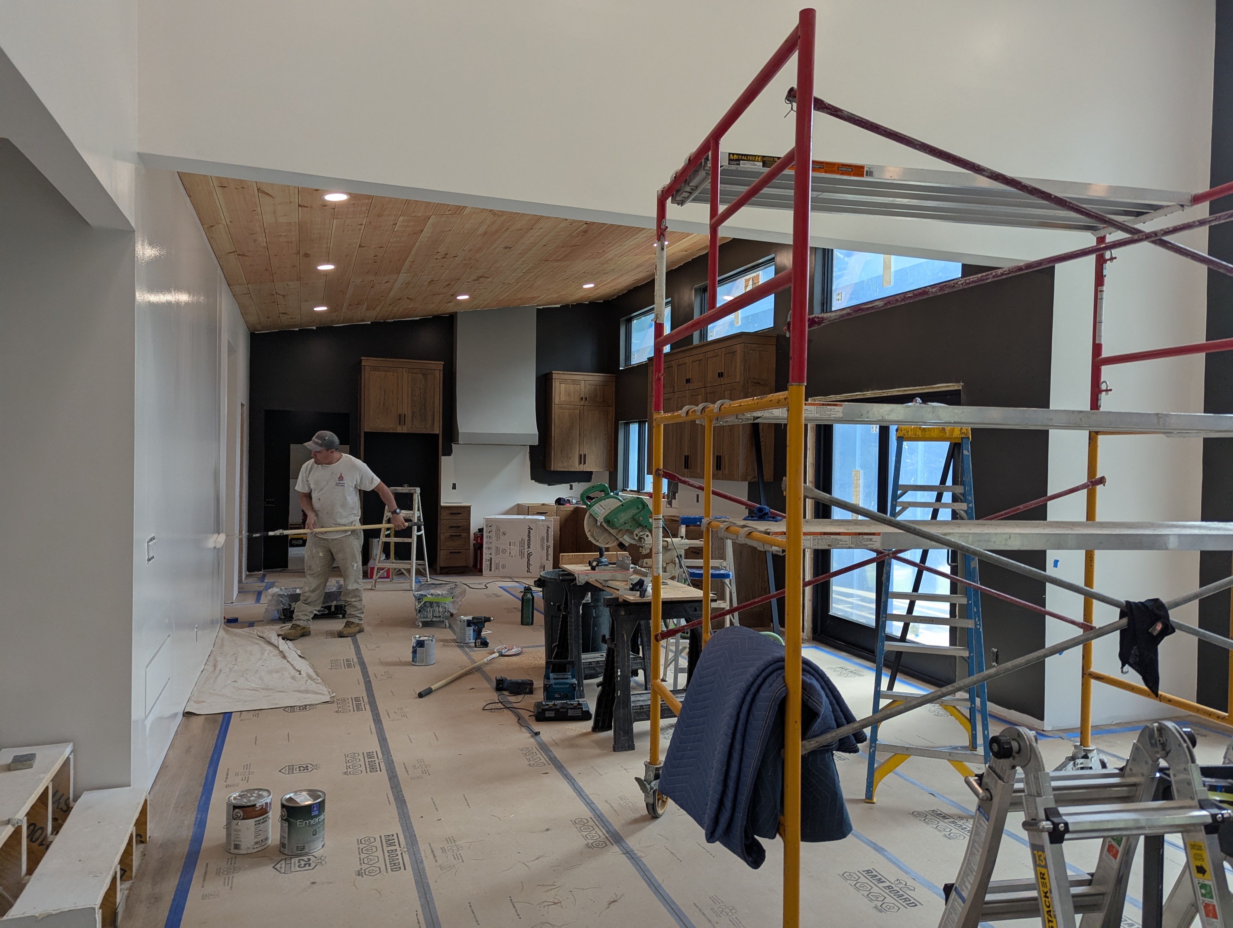 Interior home painting project in progress with scaffolding and painter.