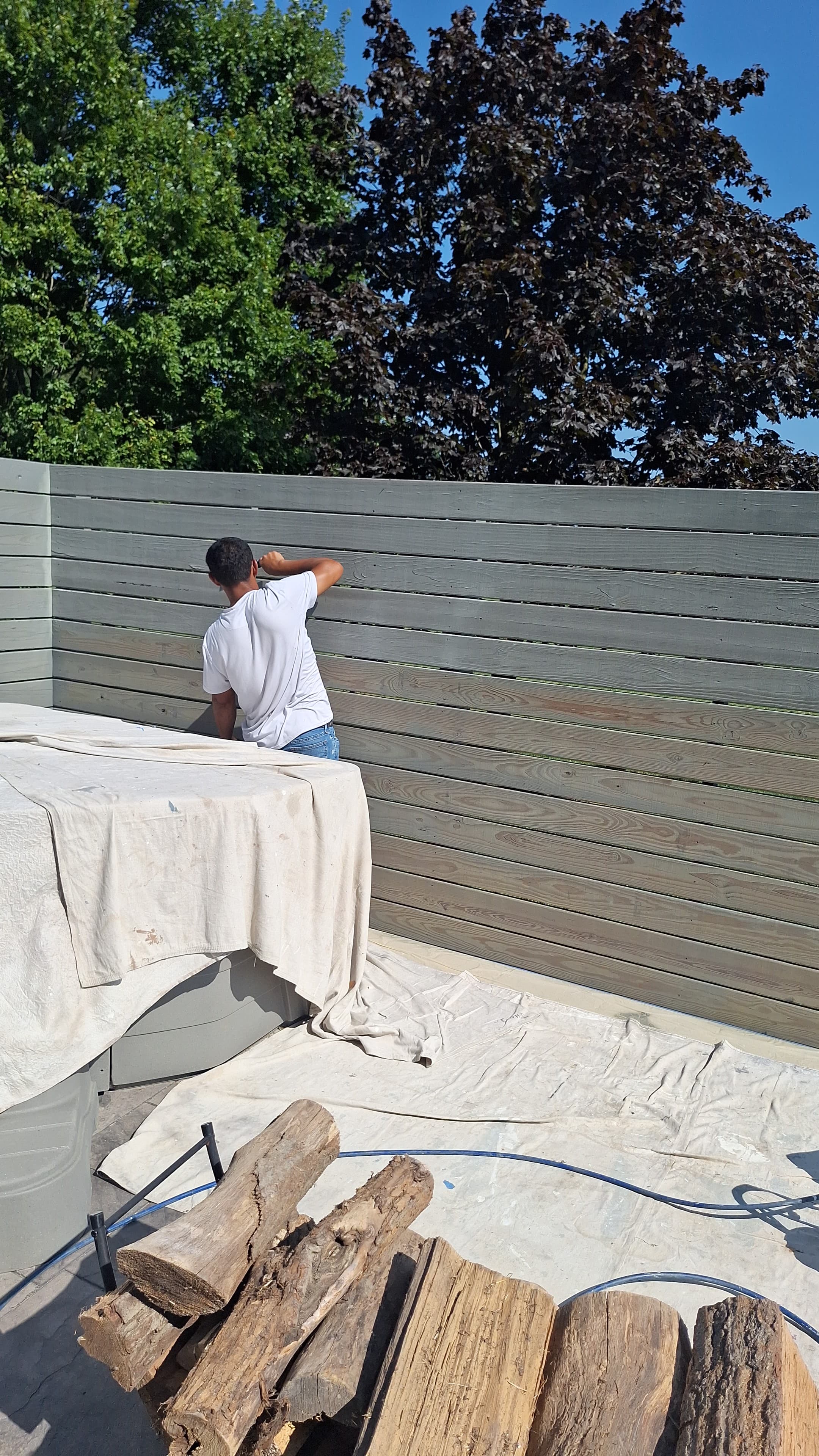 Man staining a backyard fence, landscaping project.