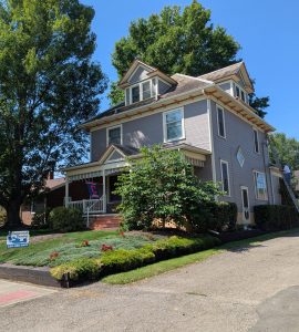 Grey house with white trim being painted. "Sugarcreek Painting" sign visible.