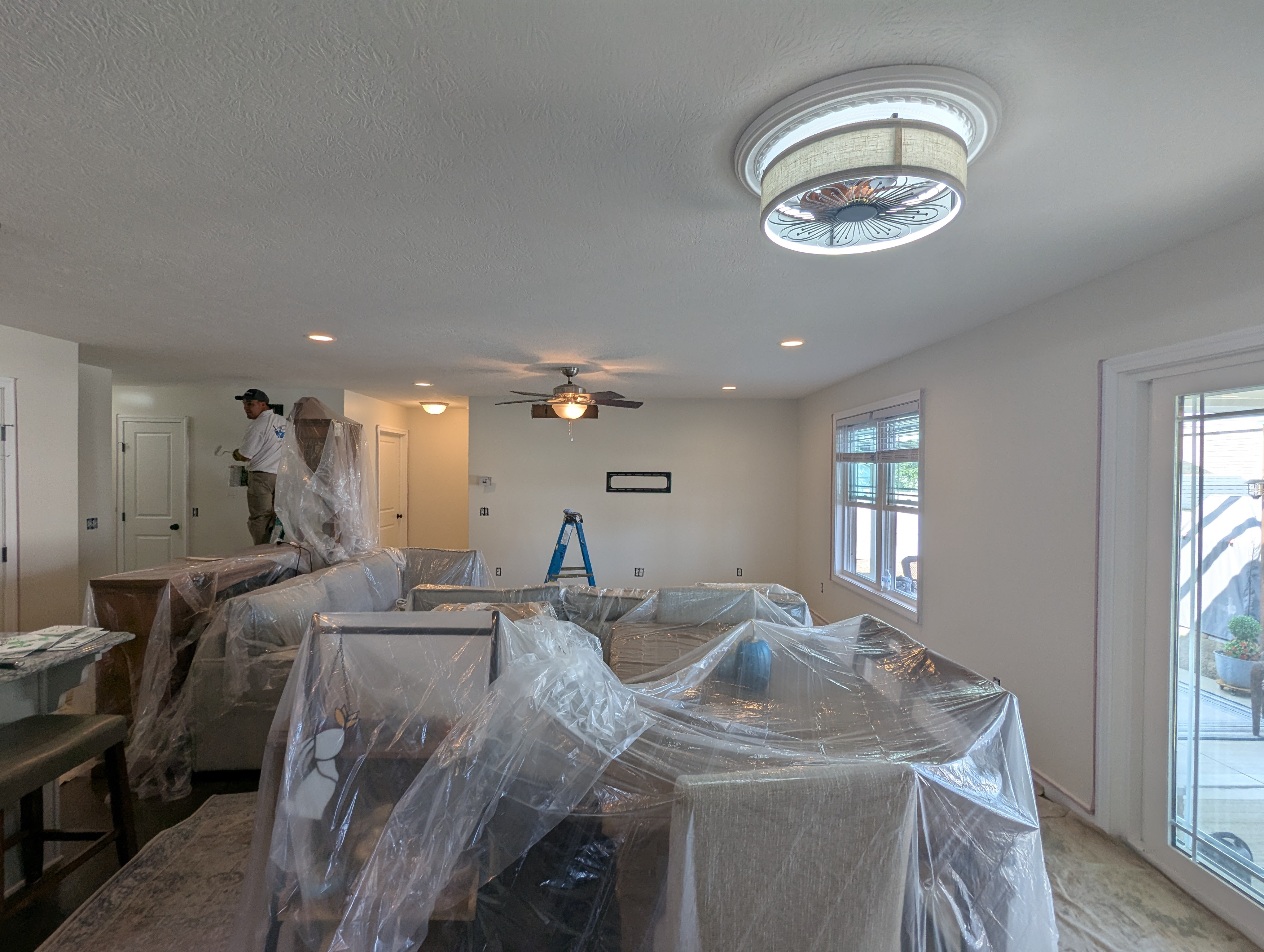 Room being painted with furniture covered in plastic sheeting.